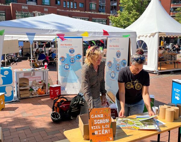 Stand 2 Personen betrachten das Wimmelbuch von RENN.nord mit Roll-Ups