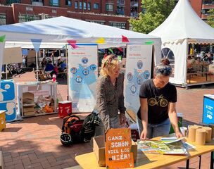 Stand 2 Personen betrachten das Wimmelbuch von RENN.nord mit Roll-Ups 