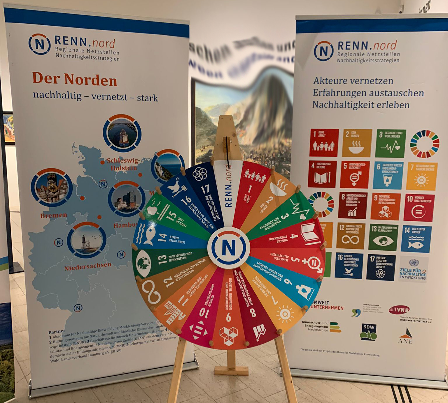 Abbildung des SDG Glücksrades mit 2 Roll-Ups zu RENN.nord Abbildung des SDG Glücksrades mit 2 Roll-Ups zu RENN.nord